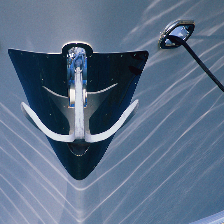 Boat front with anchor close up with water reflecting off the boat