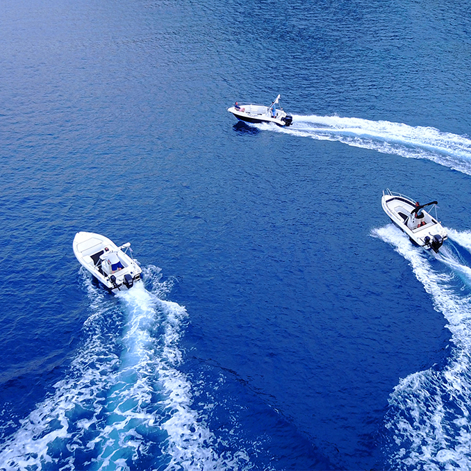Aerial drone ultra wide top down photo of synchronised powerboats cruising in high speed in deep blue open ocean sea: small boat adventures